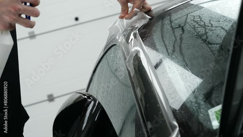 Close up of paint protection film installation on front bumper of modern luxury car. PPF is polyurethane film applied to car surface to protect the paint from stone chips, bug splatter, and abrasion.