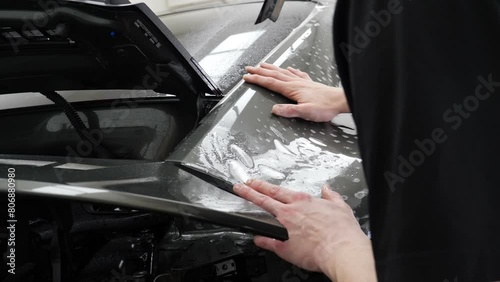 Close up of paint protection film installation on front bumper of modern luxury car. PPF is polyurethane film applied to car surface to protect the paint from stone chips, bug splatter, and abrasion.