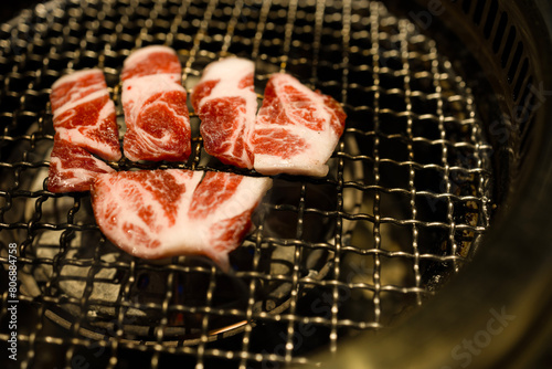  slices of beef being grilled over a charcoal fire