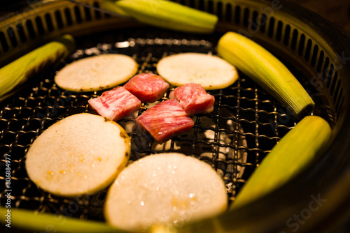  a grill where freshly prepared meat slices and vegetables are being cooked