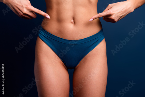 No filter cropped photo of lady underwear lingerie pointing fingers sporty tummy isolated blue color background