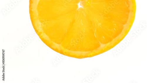 Water drop falling from orange on white background. Orange slice and water splashing, drops of juice falling from juicy fruit.