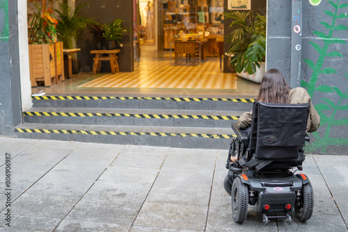 woman in an wheelchair in front of an inaccessible stairway entrance. concept, architectural barriers and motor disability