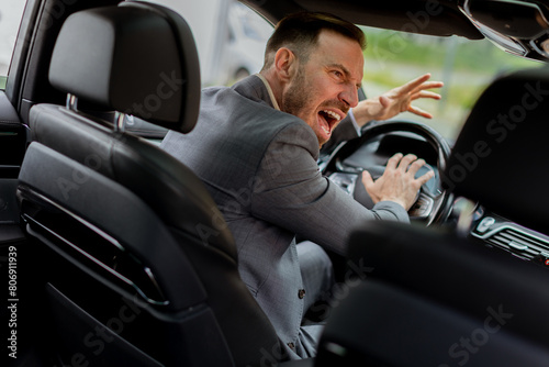 Businessman expressing intense emotion while driving car in urban setting