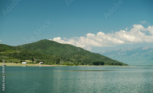 Waterfront view of picturesque mountains with blue sky and clouds. Kerkini lake, Greece