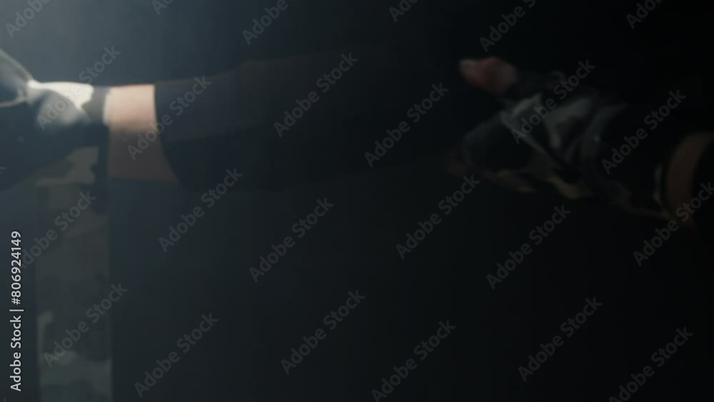 a fighter wraps bandages on his hands in the dark