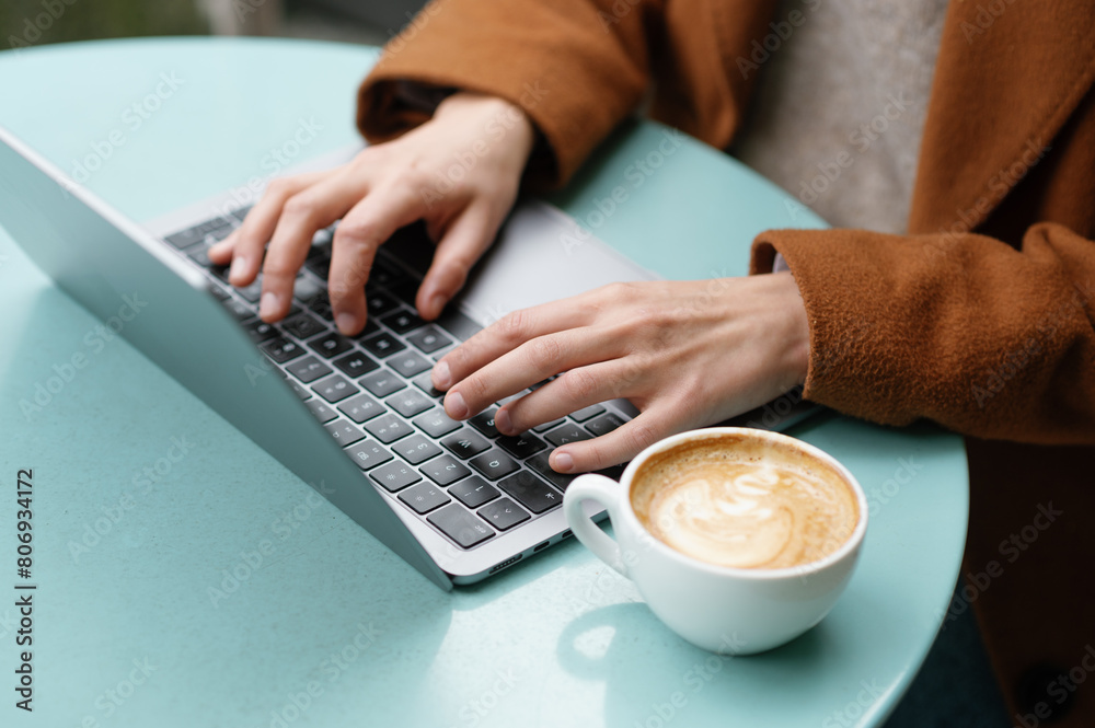 Hands of a woman using laptop in a cafeteria Hands of a woman using laptop in a cafeteria