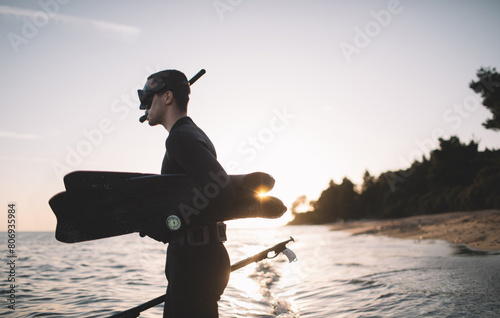 Young spearfisherman holds fins and spear gun and ready for spearfishing photo