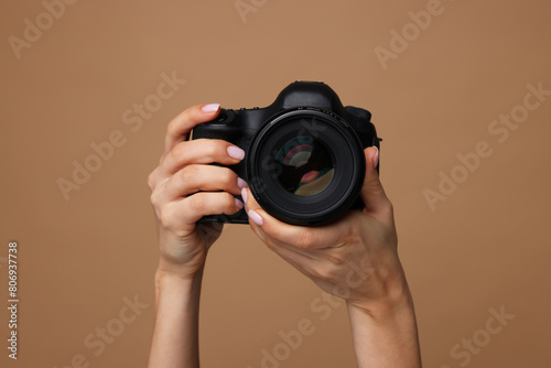 Photographer with camera on brown background, closeup photo