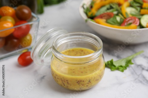 Tasty vinegar based sauce (Vinaigrette) in jar on white marble table, closeup