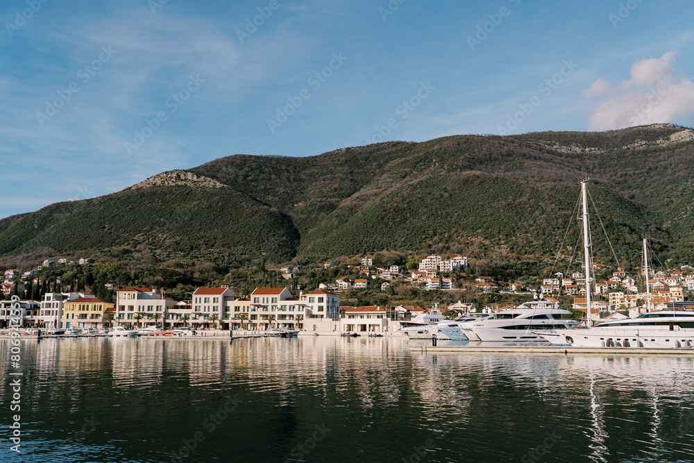 Coast of the Lustica bay with colorful houses and yachts at the pier. Montenegro