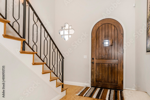 an entry way with white walls and a wooden door with a black iron railing 