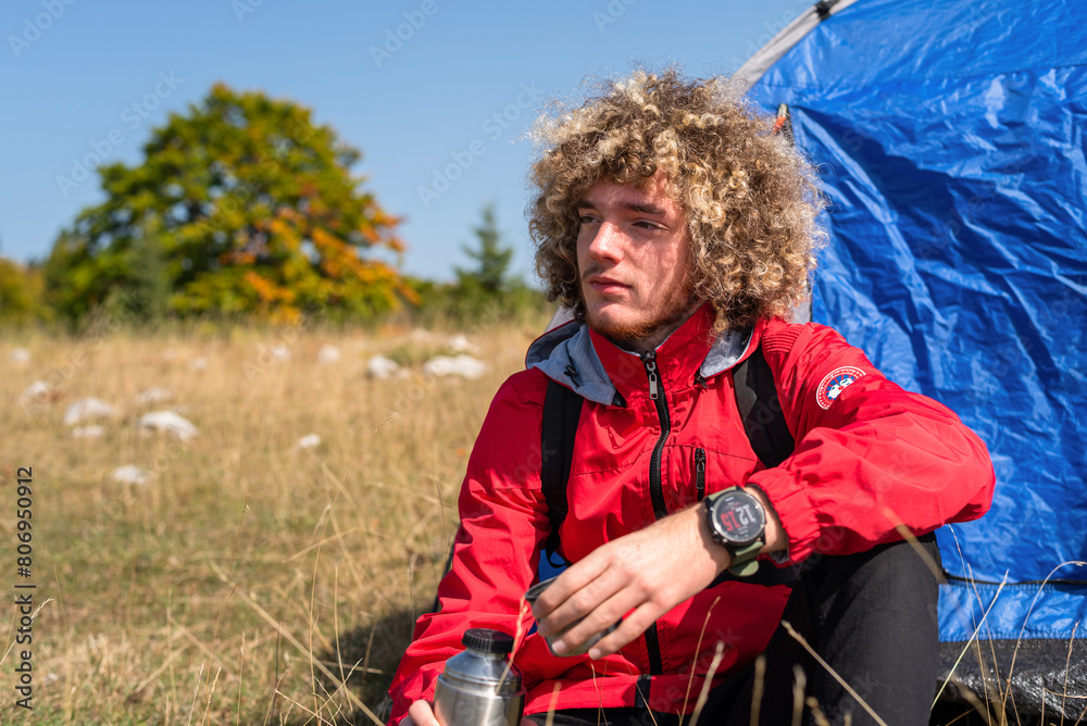 A happy young traveler enjoying while drinking a cup of coffee during the camping on the mountain forest. A happy young traveler enjoying while drinking a cup of coffee during the camping on the mountain forest.