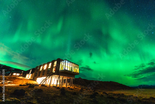 Aurora borealis, Northern lights glowing over luxury hotel on volcanic wilderness in winter at Iceland