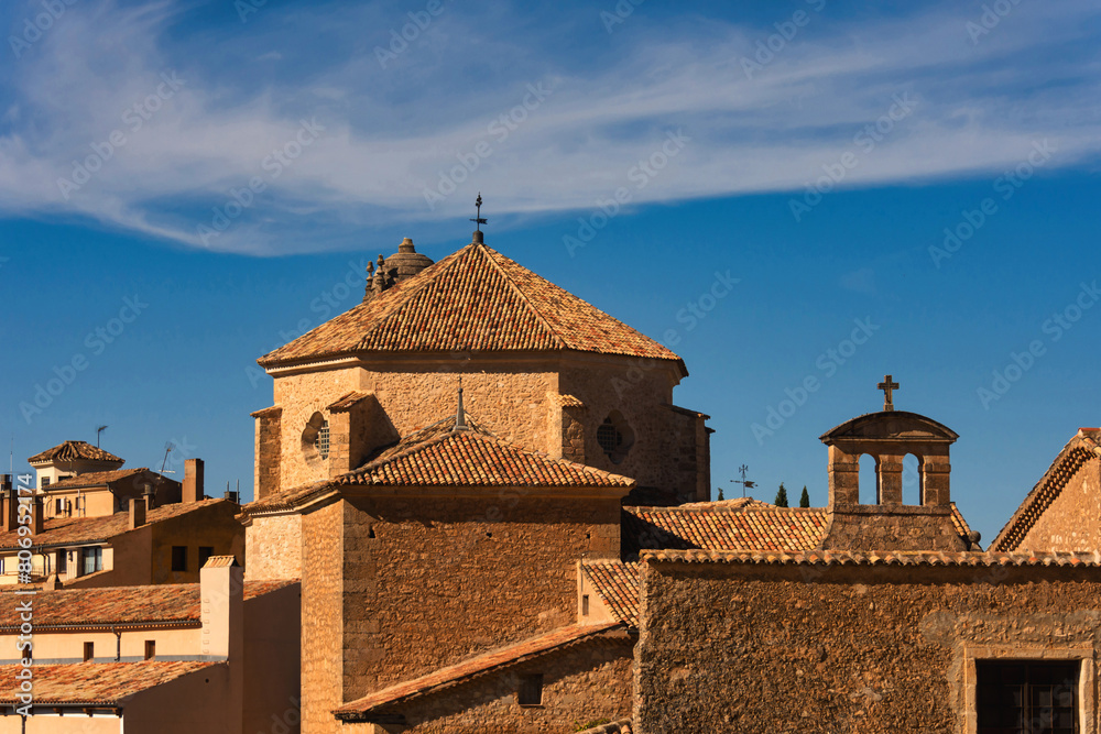 Obraz premium The rooftops of medieval houses and the dome of a church in the city of Cuenca, Spain, against a backdrop of blue sky