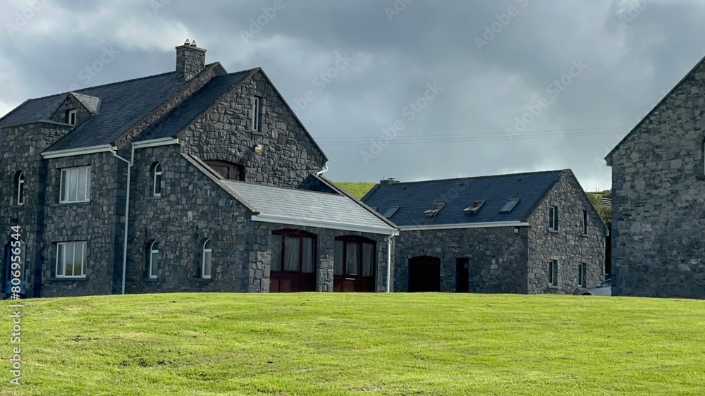 Scenic view of Irish homes on green meadow under cloudy sky Scenic view of Irish homes on green meadow under cloudy sky