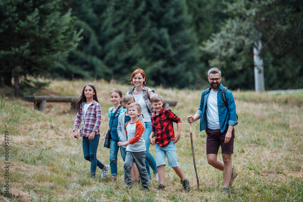 Fototapeta premium Young students learning about nature, forest ecosystem during biology field teaching class, observing wild plants. Dedicated teachers during outdoor active education.