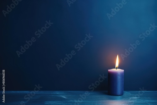 Indigo background with white thin wax candle with a small lit flame for funeral grief death dead sad emotion with copy space texture for display 