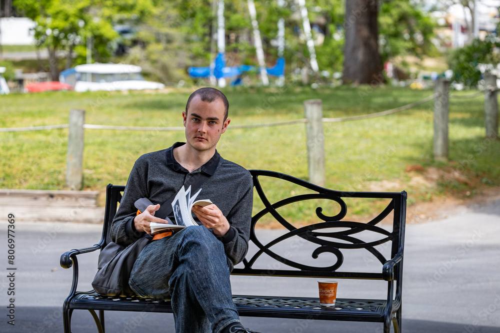 Solomons, Maryland USA A young man sits on a bench reading a book. Solomons, Maryland USA A young man sits on a bench reading a book.