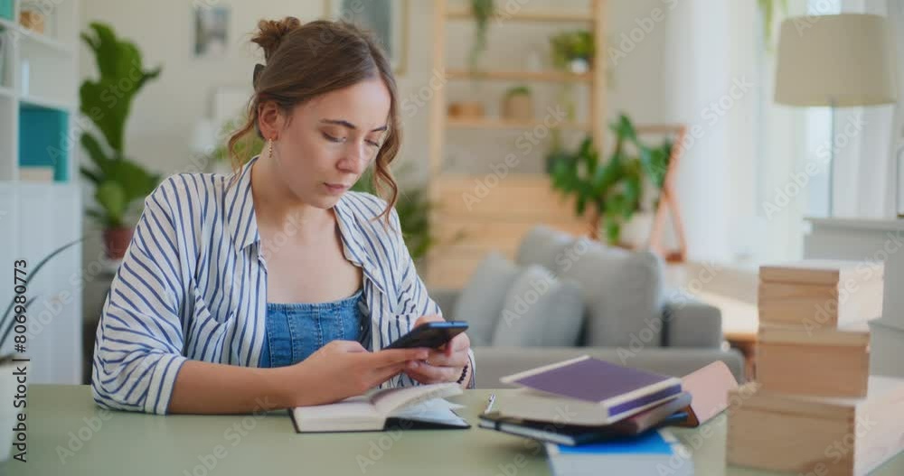 Female Student Browsing Smartphone While Learning at Desk Female Student Browsing Smartphone While Learning at Desk