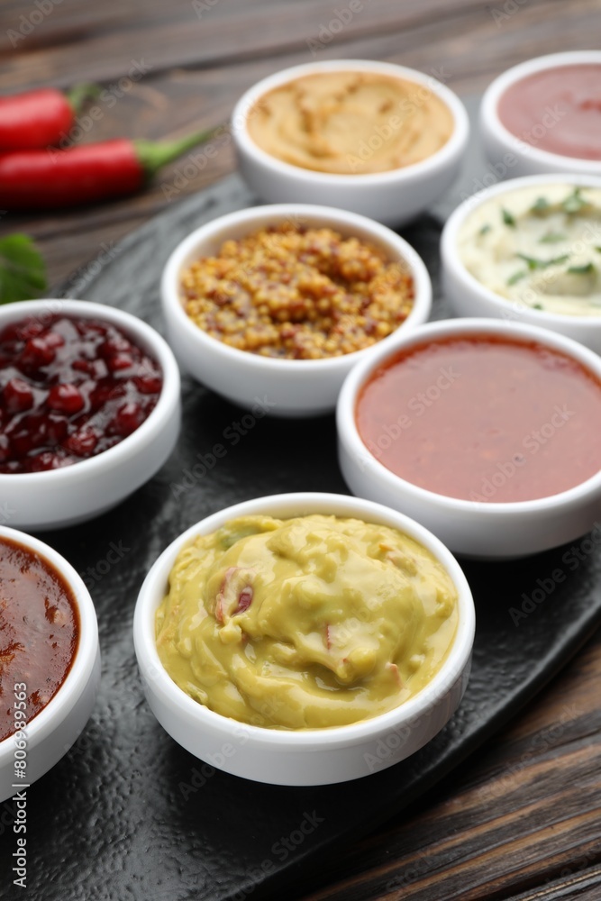 Different tasty sauces in bowls on wooden table, closeup Different tasty sauces in bowls on wooden table, closeup