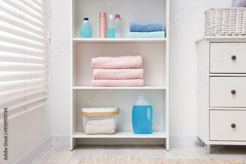 Shelving unit with stacked clean towels and toiletries in room