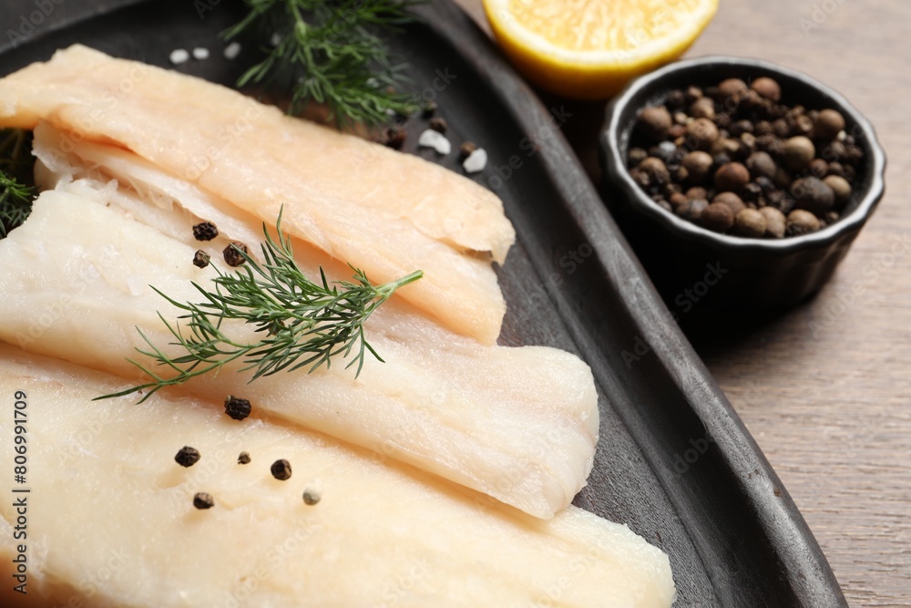 Raw cod fish, dill and spices on wooden table, closeup Raw cod fish, dill and spices on wooden table, closeup