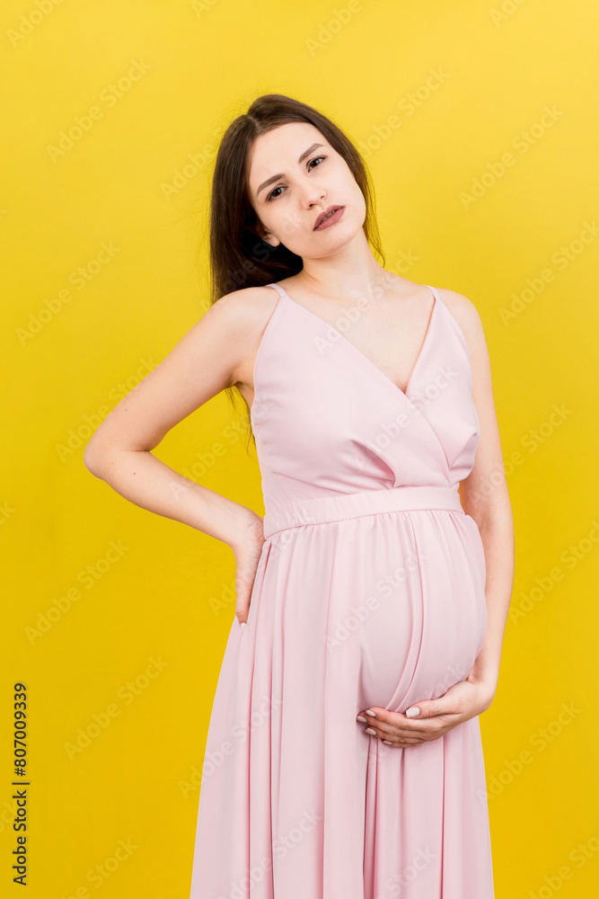 Pregnant woman with a pain in her back on colored Background isolated Pregnant woman with a pain in her back on colored Background isolated