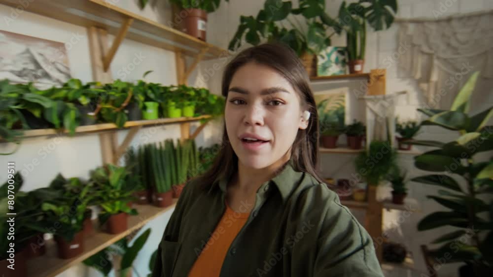 Medium of young Caucasian female houseplants shop employee in casual outfit making video content of potted plants for home gardening, advertising her store in social media Medium of young Caucasian female houseplants shop employee in casual outfit making video content of potted plants for home gardening, advertising her store in social media
