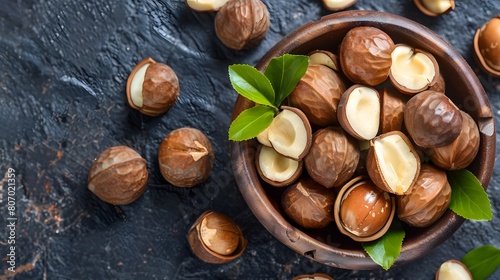 Macadamia Nuts in a Wooden Bowl on Rustic Dark Background with Green Leaves