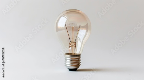  A light bulb against a white backdrop, reflecting a bulb's image on its side