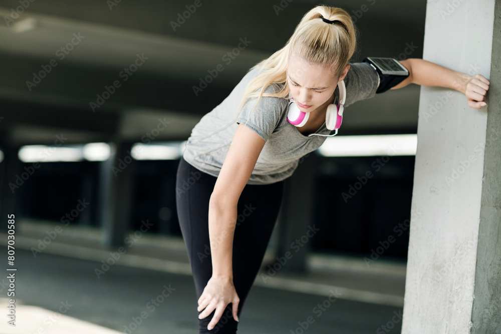 Fototapeta premium Active young woman working out with headphones outside