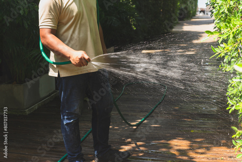 Man watering plant in the garden with hose.