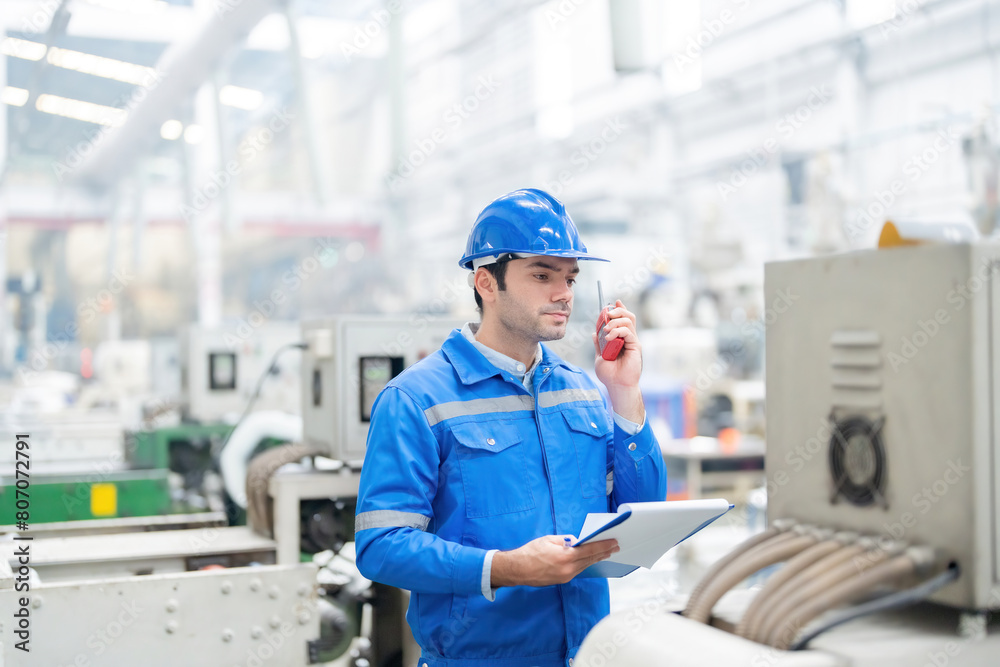 An engineer from Europe oversees plastic and steel machinery for global export, equipped with laptop and radio, ensuring quality while wearing safety gear. An engineer from Europe oversees plastic and steel machinery for global export, equipped with laptop and radio, ensuring quality while wearing safety gear.