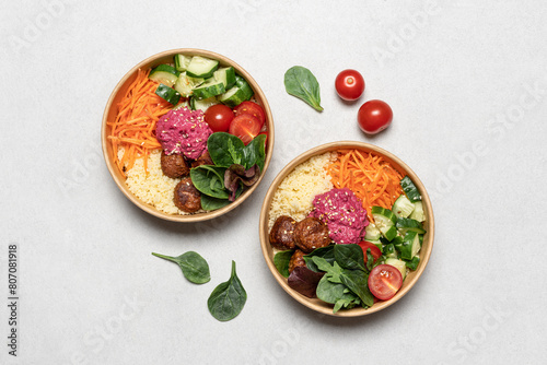 Healthy take away salad with vegan meatballs, vegetables, couscous and beetroot hummus  in disposable eco friendly paper containers on white background, top view