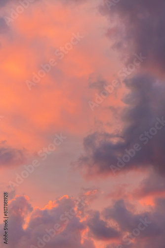 Vivid sunset cloudscape with warm orange and pink hues blending into soft purple © Elena