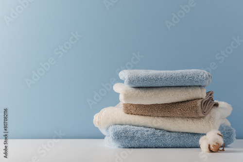 Stack of delicate colored cotton towels with cotton buds on  blue background