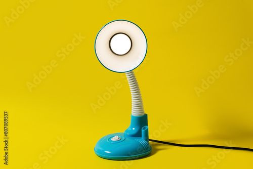 Bedside table lamp in blue color isolated on yellow background. Soft neutral light from a table lamp. Blue bedside lamp viewed from the side.