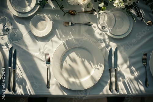 Overhead view of pristine plates and utensils on a table  set amidst the romantic ambiance of a wedding celebration.