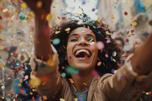 Woman laughing joyfully while tossing confetti into the air with friends at a lively celebration party.