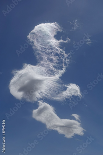 white cloud with strange shape spread over blue sky on windy day