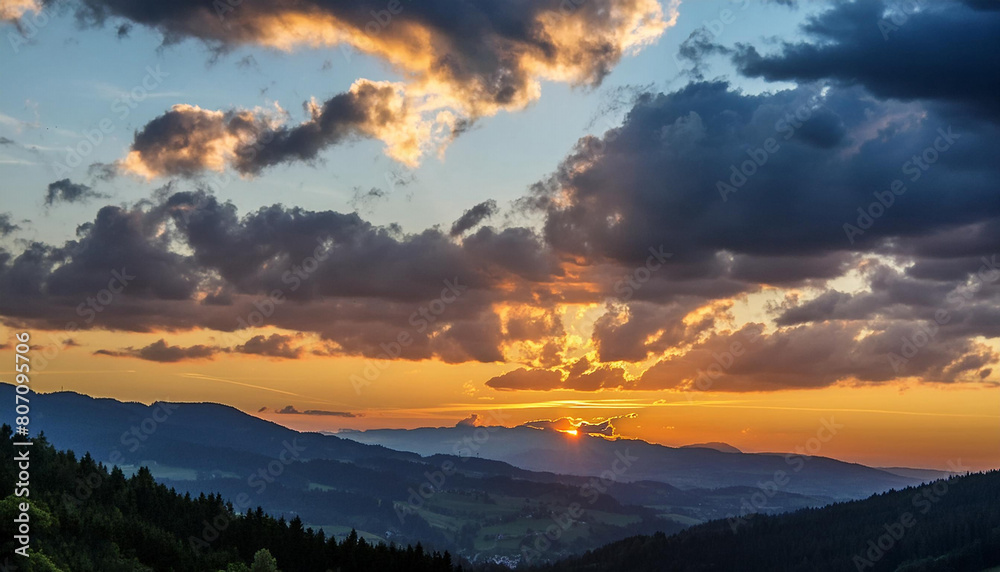 Obraz premium A stunning sunset over the mountain range with the sun shining through the clouds, creating a beautiful afterglow in the sky