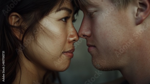 Young couple faces each other head against head eye closed nose against nose Asian female Caucasian male in love
