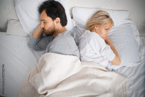 Unhappy sad couple, family, bearded man, woman, husband, wife lay in bed, turned away back to back. Unlove crisis, sexual problem issues, relationship conflict, divorce - concept image
