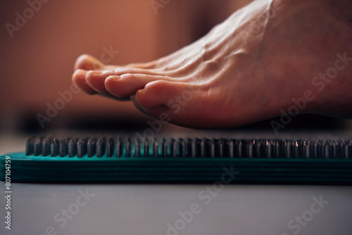 Yoga for beginners, the beginning of practice of standing on nails. A woman's foot hovered over the sharp nails of the Sadhu Board. The first step of  yoga exercise.