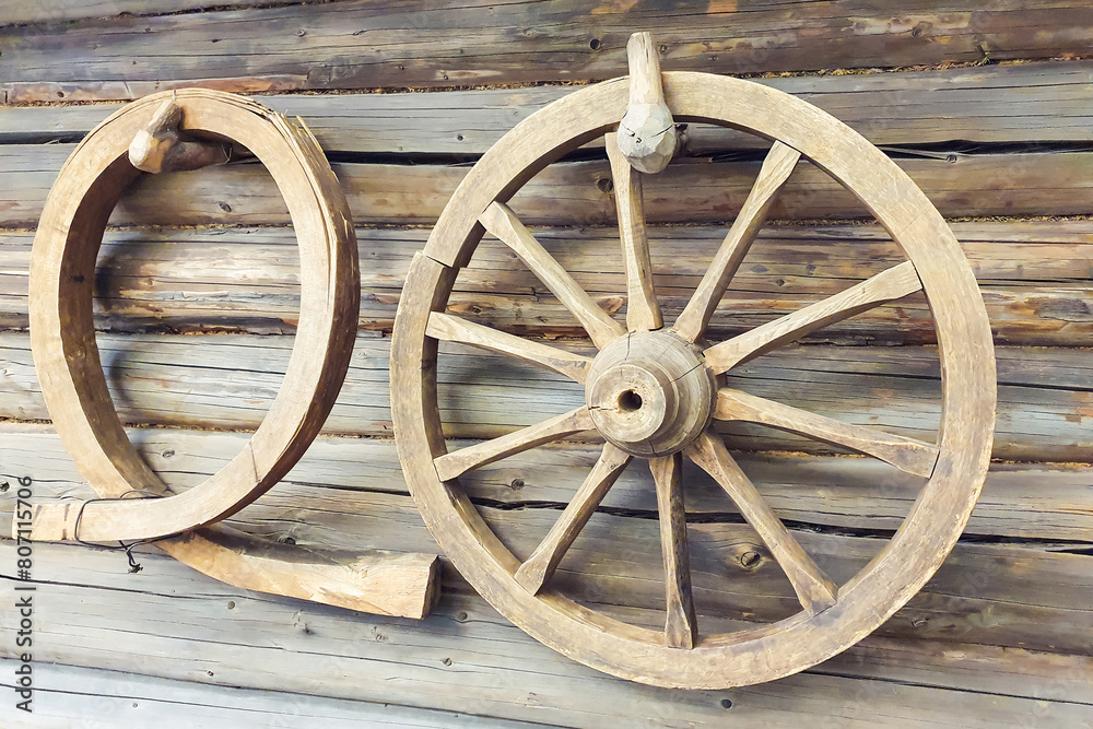 Old wooden wheel and wooden clamp or yoke on wall of vintage log house
