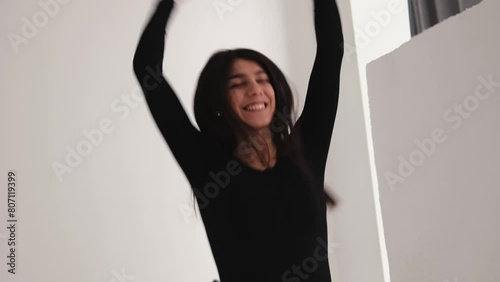 A young happy dark-haired woman is dancing in a photo studio.
