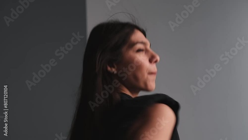 A young attractive dark-haired woman is dancing in a photo studio.The woman touches her fluttering hair with her hands.