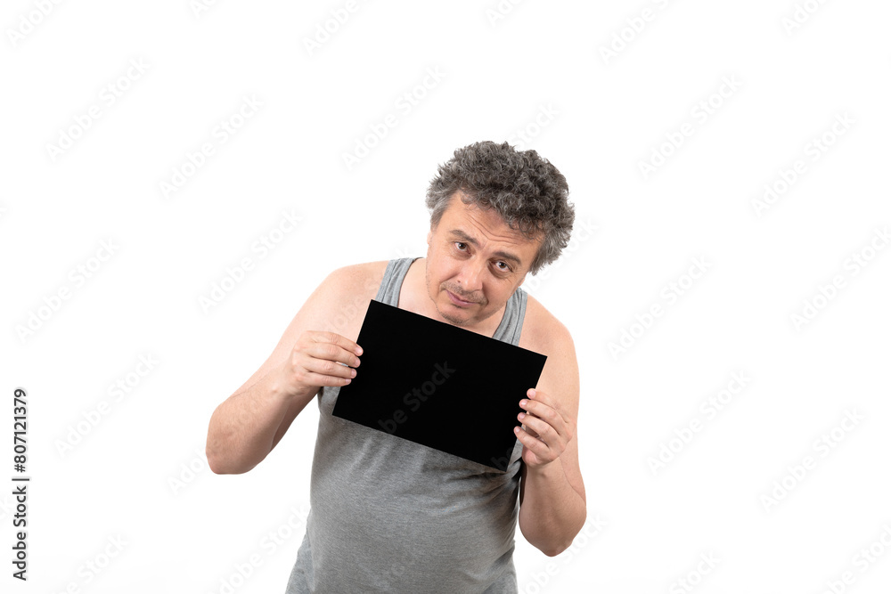 A shaggy gray-haired middle-aged man with stubble in a sleeveless T-shirt holds a black sign without an inscription in his hands A shaggy gray-haired middle-aged man with stubble in a sleeveless T-shirt holds a black sign without an inscription in his hands