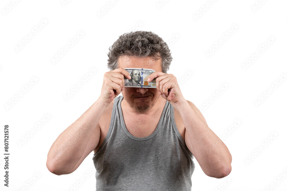 A shaggy gray-haired middle-aged man with stubble wearing a sleeveless T-shirt holds a 100 US dollar bill in his hands A shaggy gray-haired middle-aged man with stubble wearing a sleeveless T-shirt holds a 100 US dollar bill in his hands